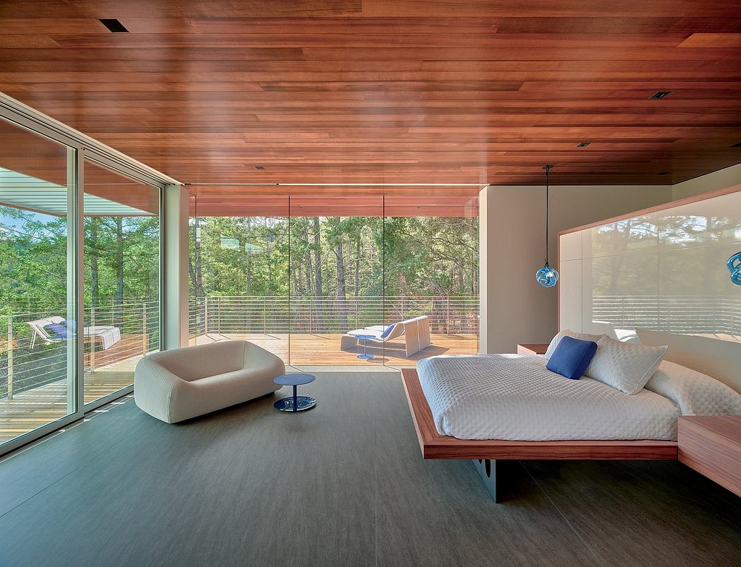 Expansive wood-paneled bedroom with floor-to-ceiling windows, cozy seating, and modern furnishings.