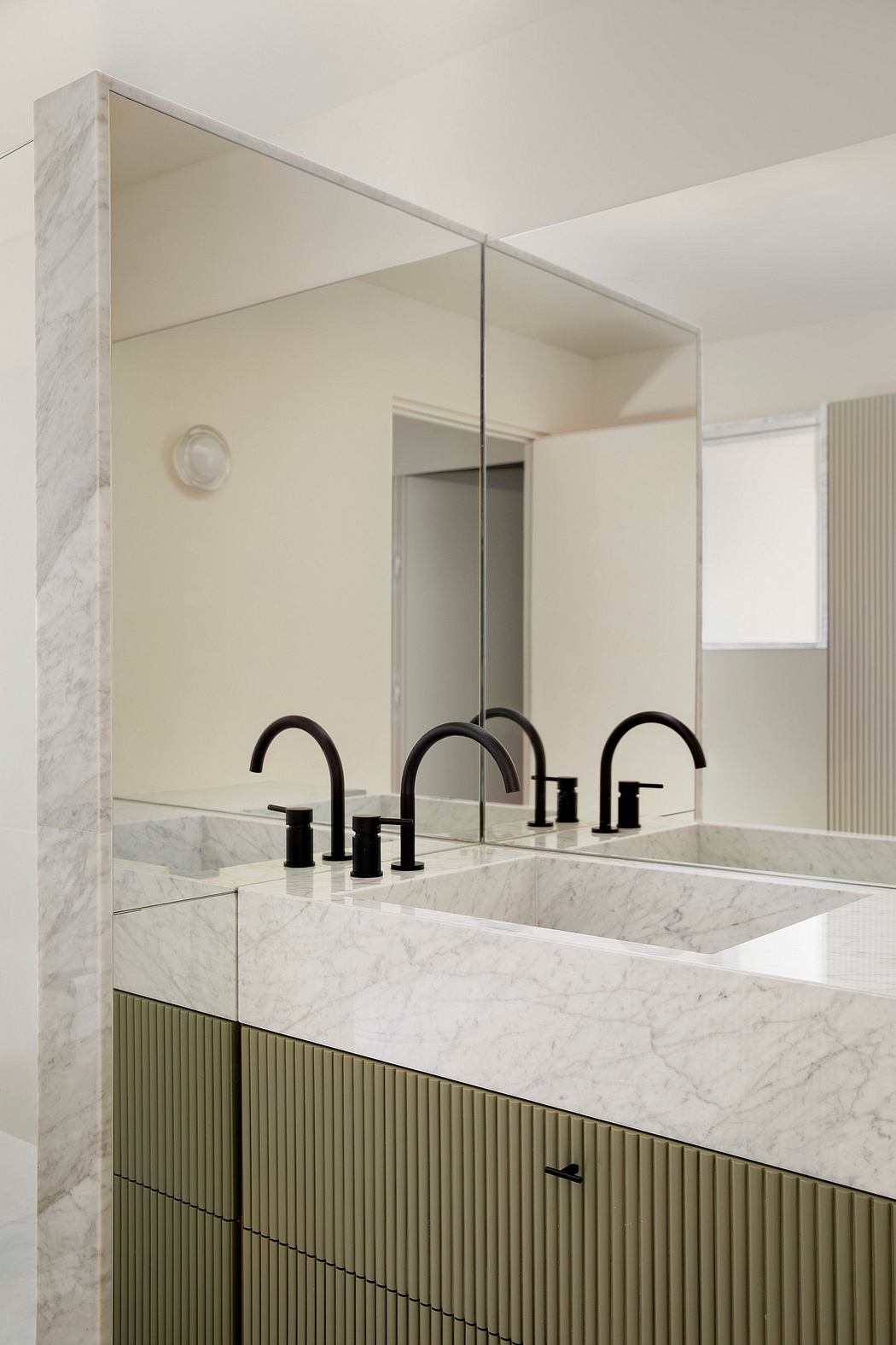 Sleek, modern bathroom with marble vanity, black faucets, and minimalist mirror frame.