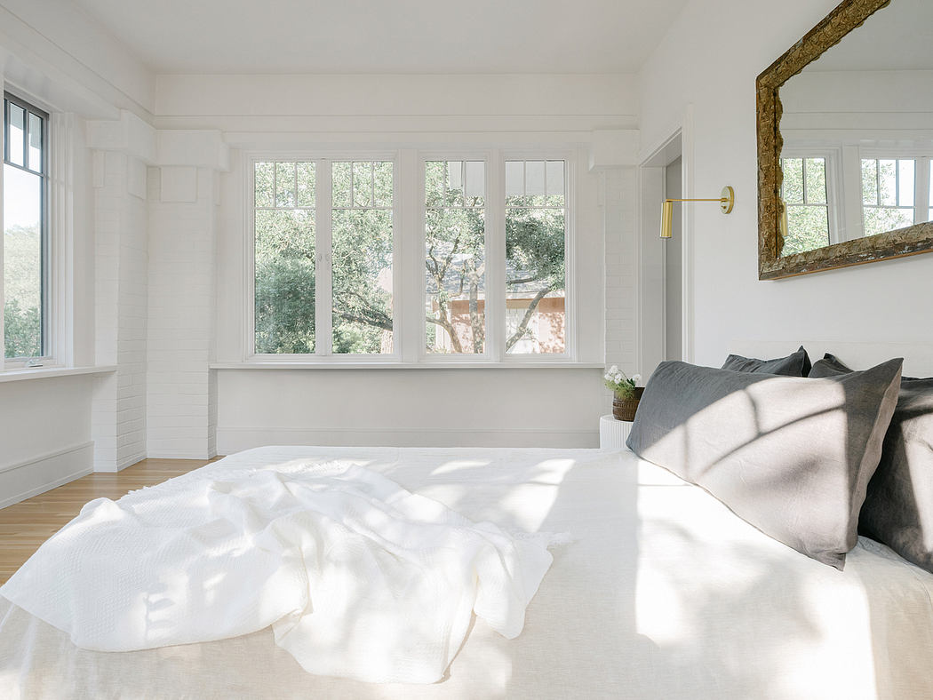 Bright and airy bedroom with large windows overlooking lush greenery, minimal decor.