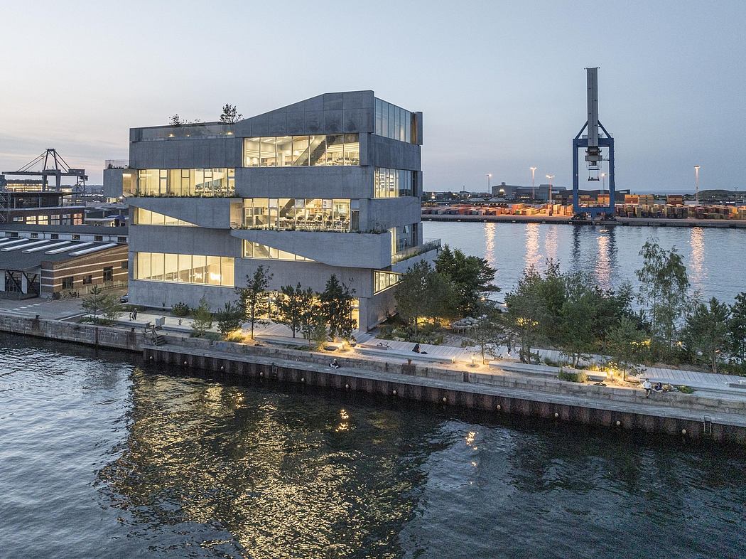 Striking modern building with glass and concrete façade overlooking a harbor.