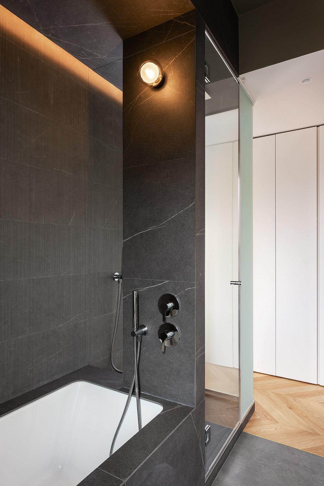 Sleek, modern bathroom design with dark tiled walls, recessed lighting, and glass shower enclosure.