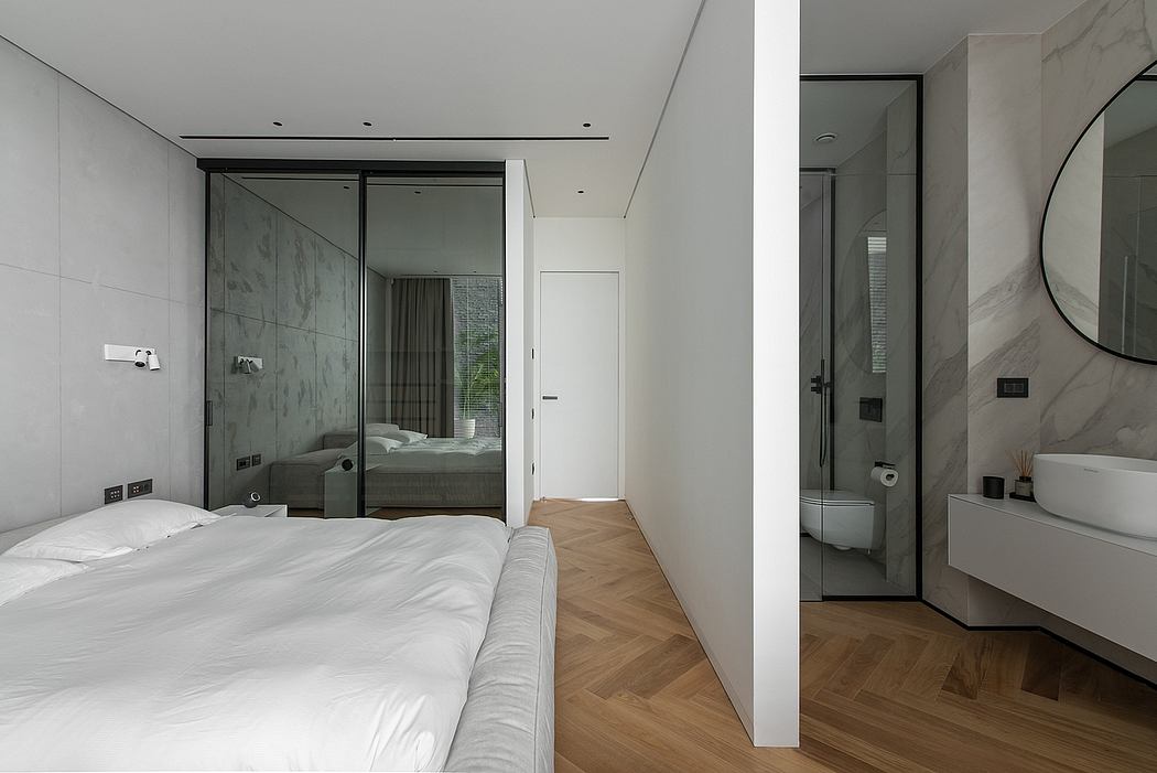 Modern minimalist bedroom with glass wall, herringbone wood flooring, and spa-like bathroom.