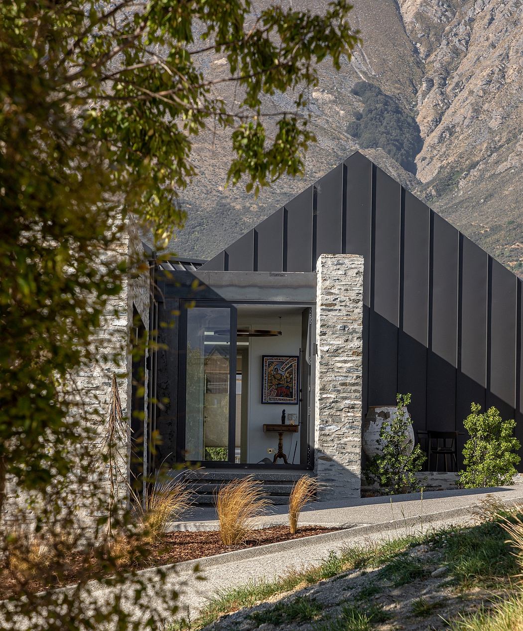 A modern, contemporary home with a stone-clad exterior, a gabled roof, and a prominent entryway.
