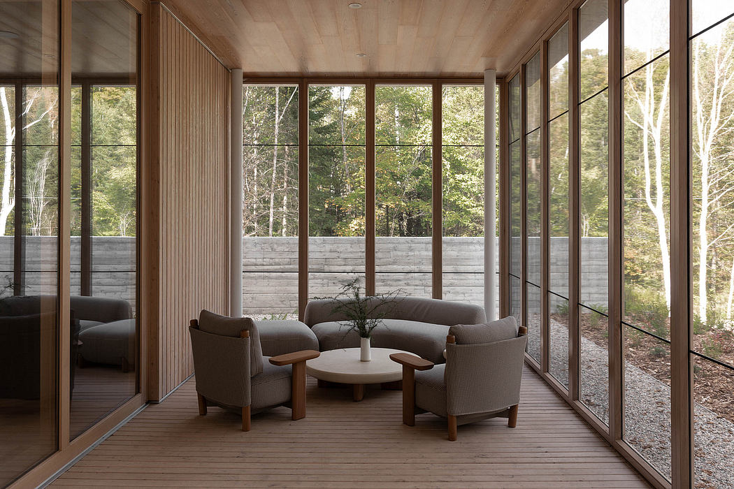 A cozy, rustic living room with large windows overlooking a lush forest.