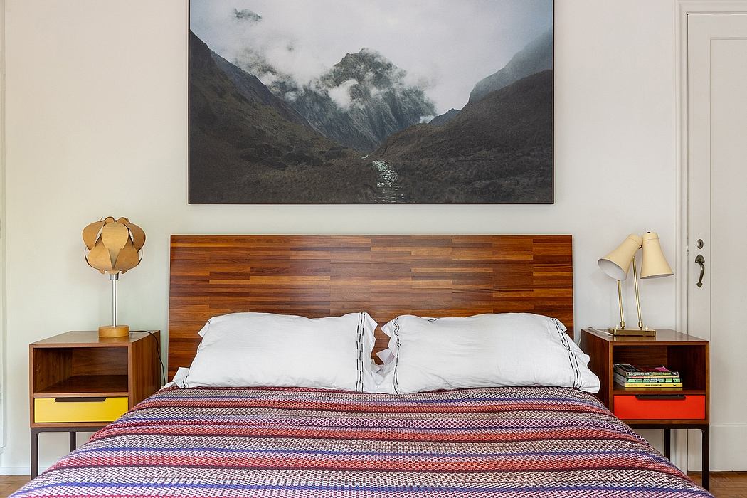 Cozy bedroom with wooden headboard, nightstands, and lamps; vibrant patterned bedspread.