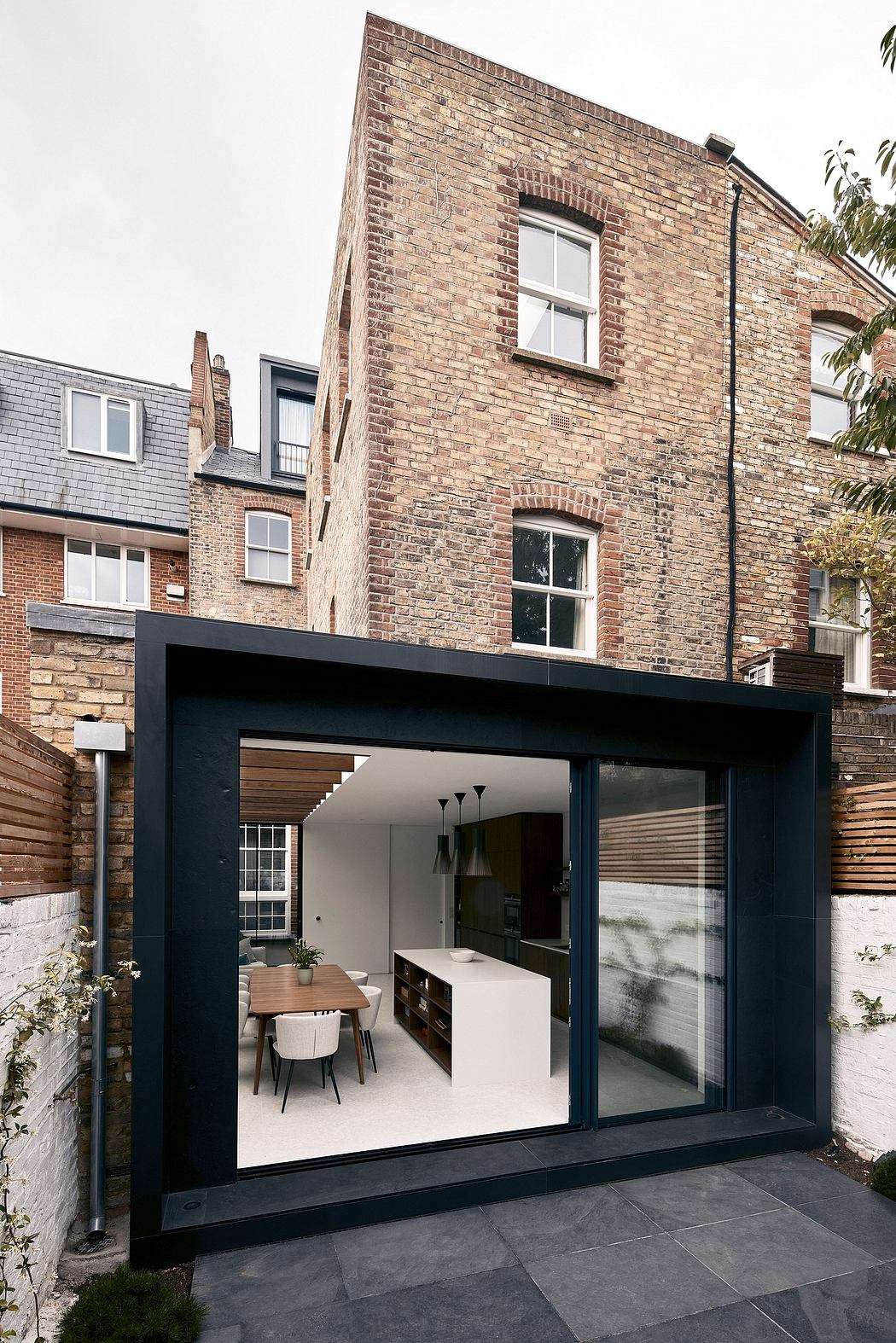 A modern extension with large black-framed windows, integrated into a brick building.