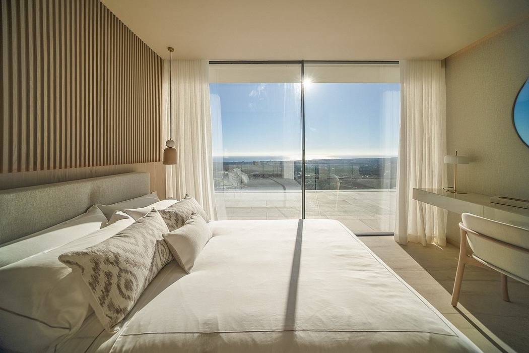 A modern, spacious bedroom with large windows offering a panoramic view of the landscape.