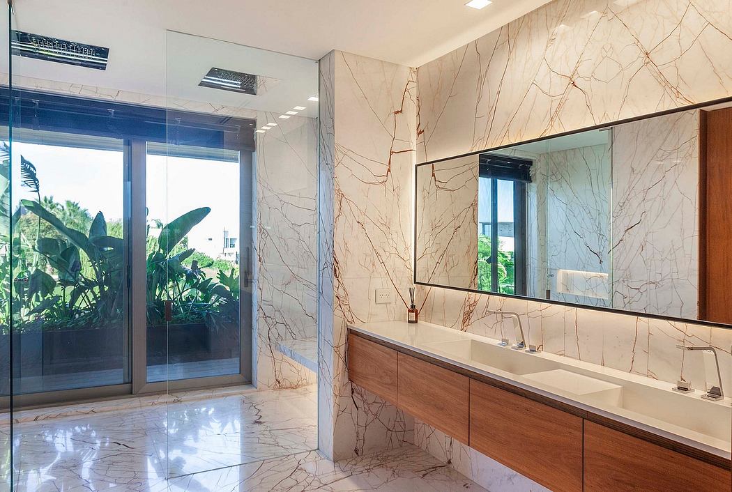 Luxurious bathroom with marble walls, wooden vanity, and large windows overlooking greenery.