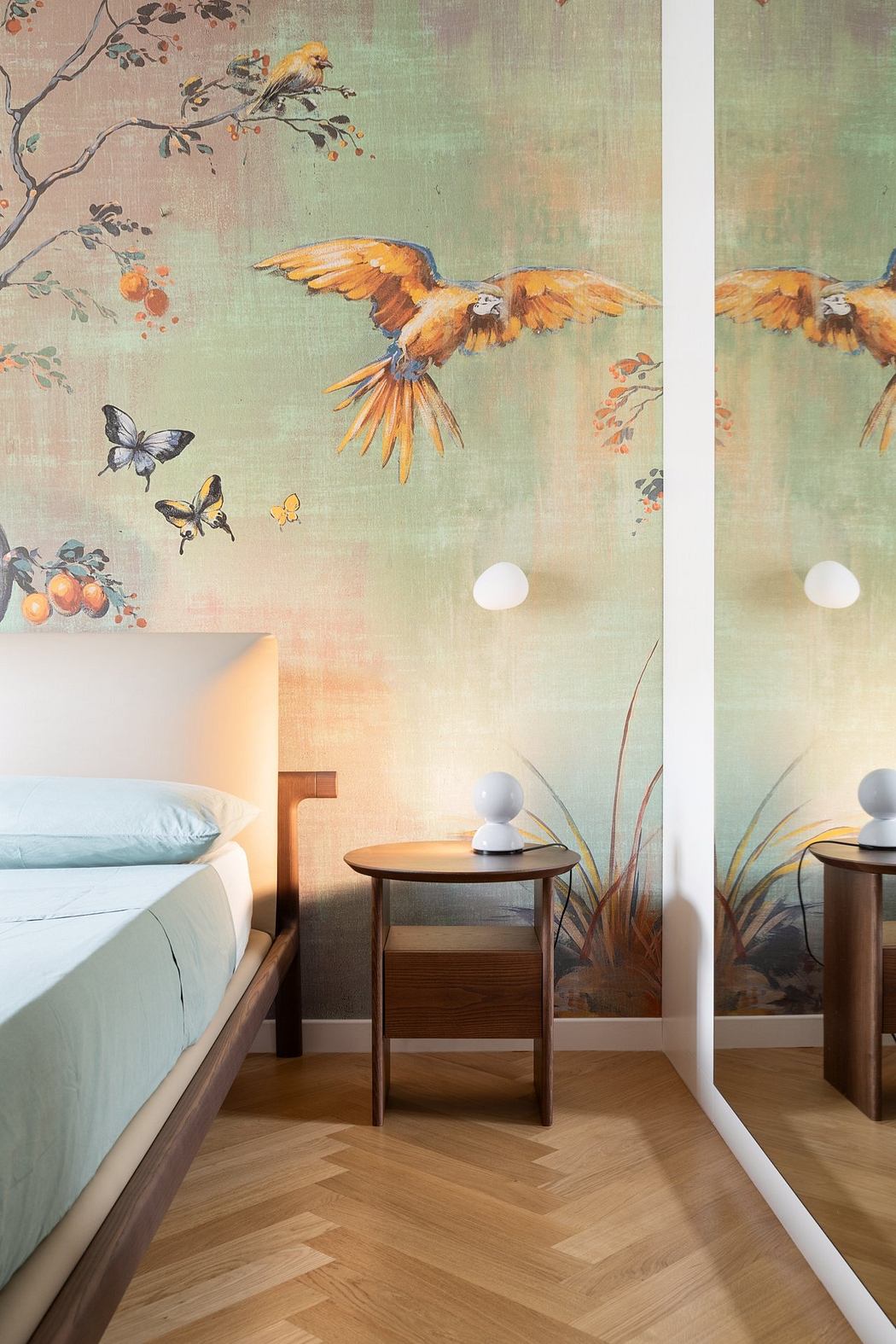 Cozy bedroom with nature-inspired mural, wood furniture, and herringbone flooring.