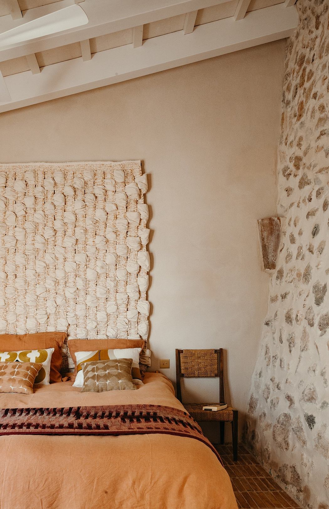 Cozy bedroom with textured walls, patterned bedding, and rustic wooden furnishings.