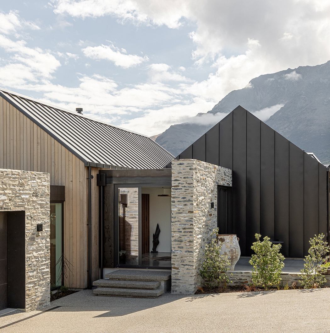 A modern mountain retreat with a striking stone and metal facade and an inviting entrance.