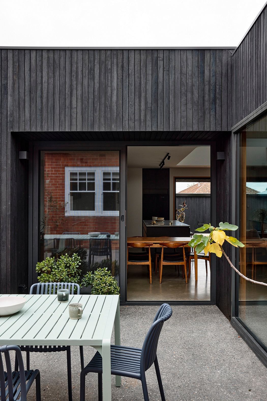 A modern home with a dark wooden facade, open-plan interior, and a cozy patio.