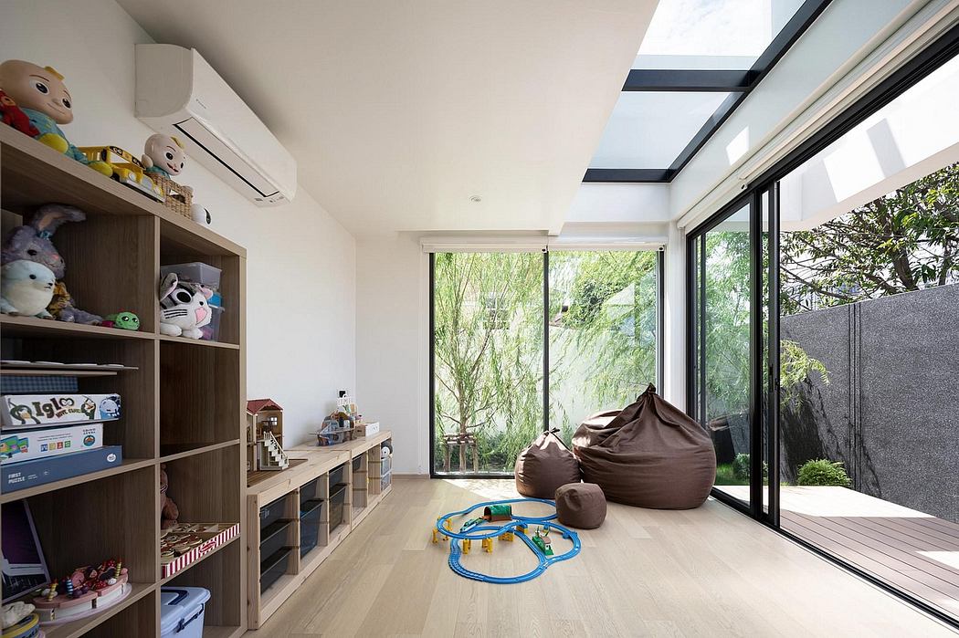 Bright, spacious children's playroom with large windows, wooden flooring, and shelving units.