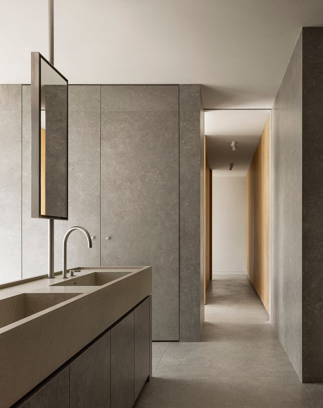 Minimalist bathroom with a sleek concrete vanity and a hallway leading to another room.