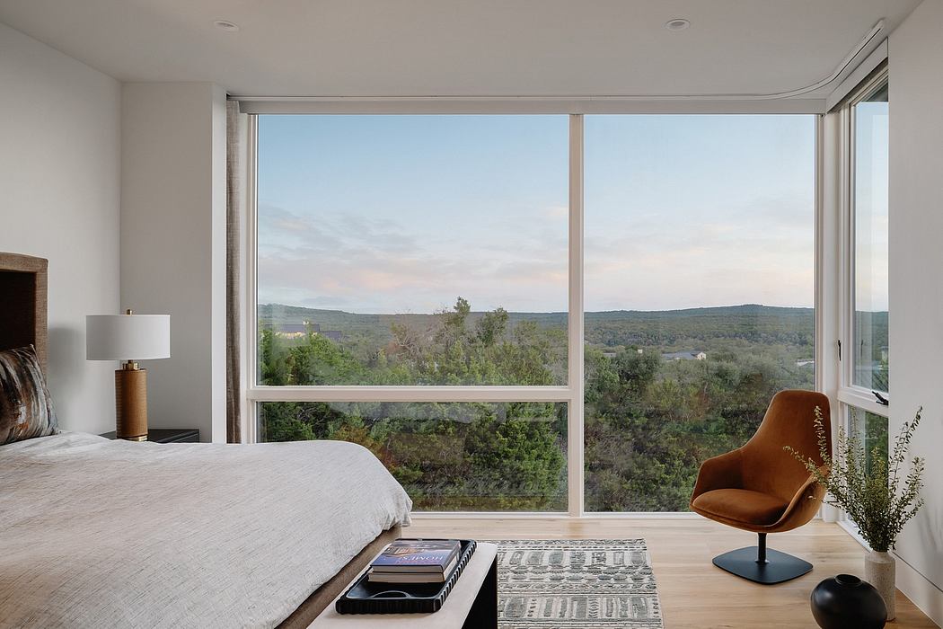 Spacious bedroom with expansive windows overlooking lush green landscape.