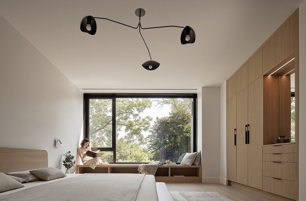 Minimalist bedroom interior with large window, wooden furnishings, and modern lighting fixture.