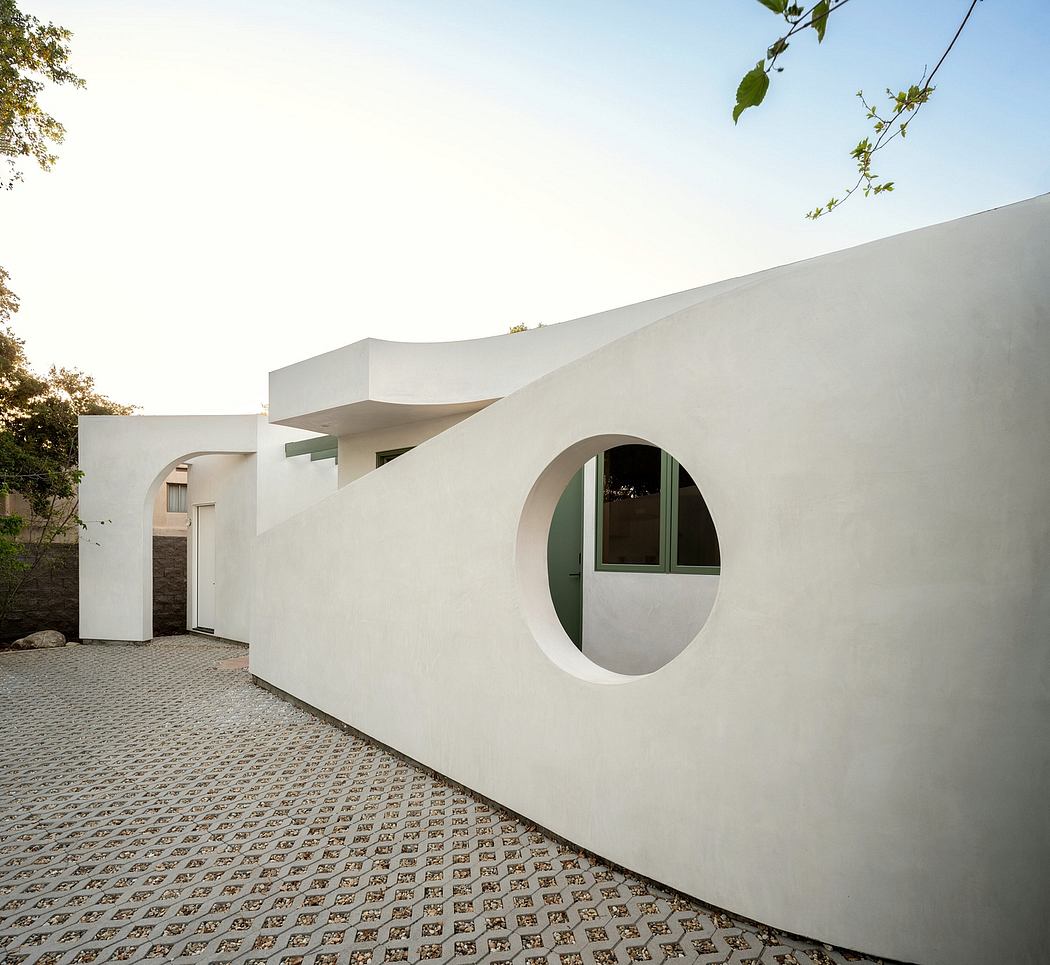 A modern, minimalist building with distinctive arched windows and a textured, paved exterior.