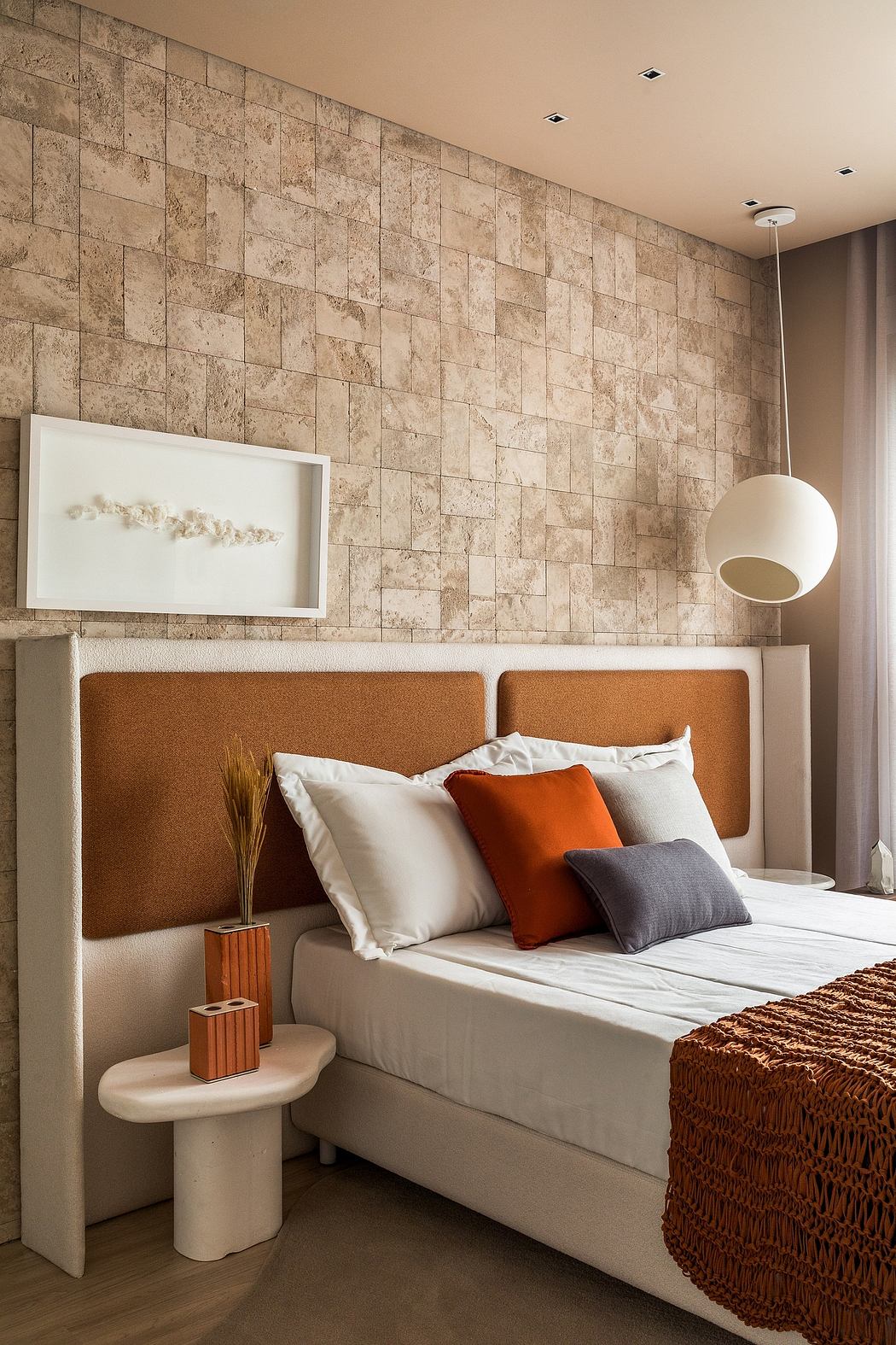 Warm-toned, modern bedroom with textured stone wall and minimalist furnishings.