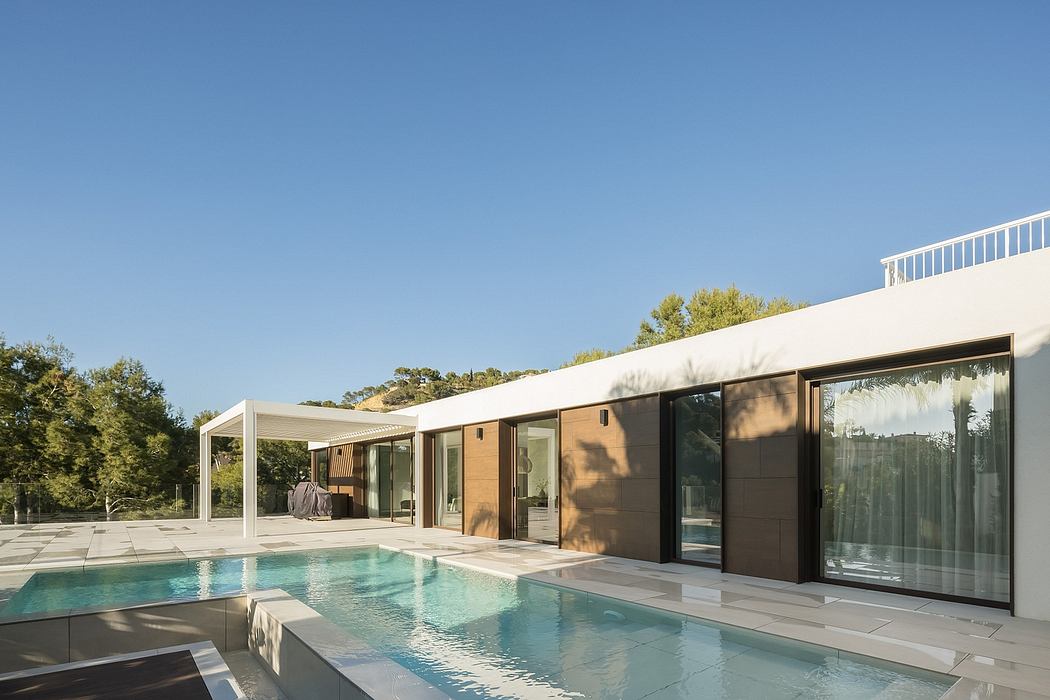 Modern single-story home with an expansive outdoor pool and patio area surrounded by lush vegetation.