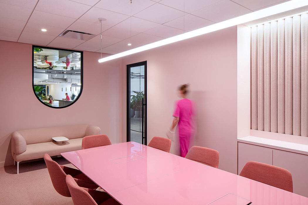 A modern, bright pink room with a large glass window, minimalistic furniture, and a person in motion.