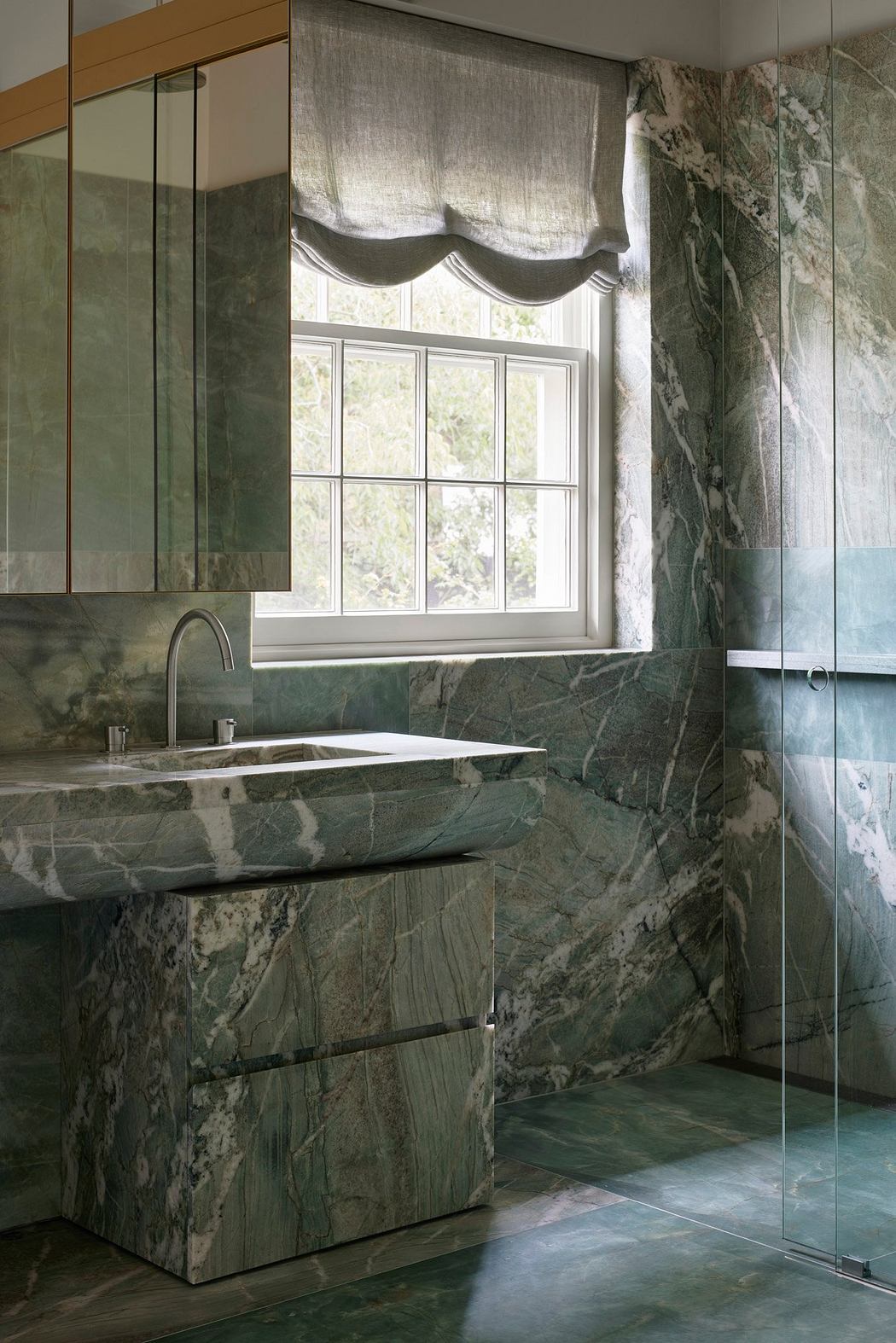 Luxurious bathroom with floor-to-ceiling marble walls, modern vanity, and large window.