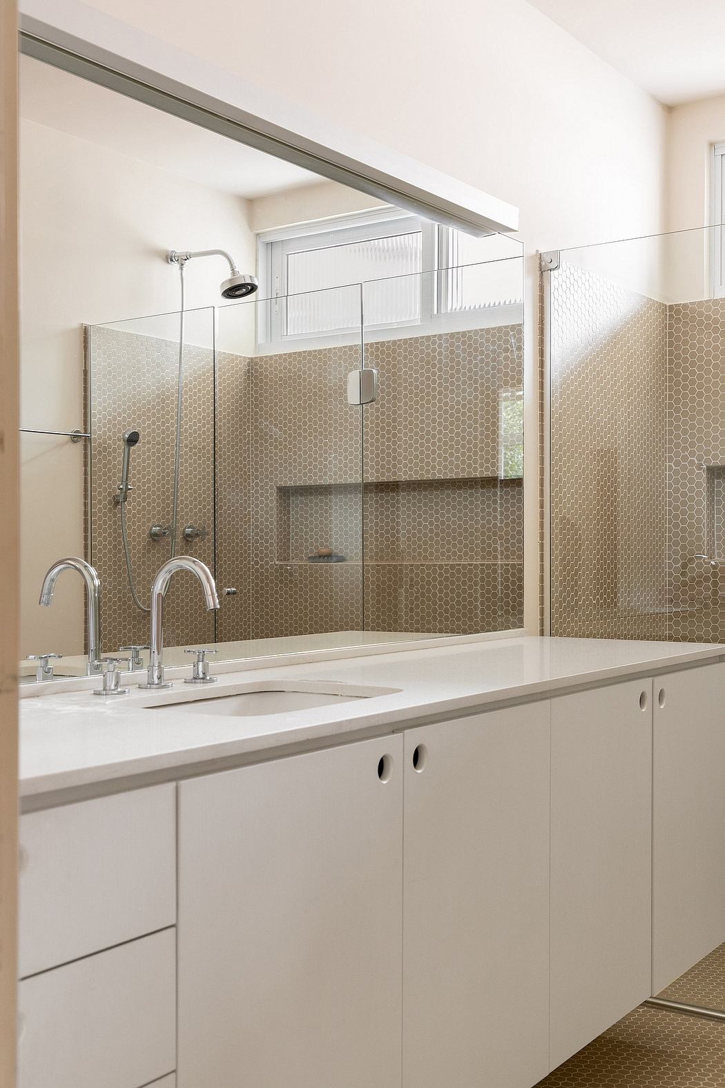 Sleek modern bathroom with a tiled backsplash, vanity, and glass shower enclosure.