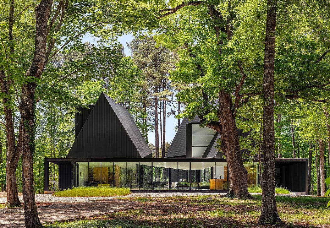 Striking modern forest home with triangular roofs, floor-to-ceiling windows, and wood interiors.