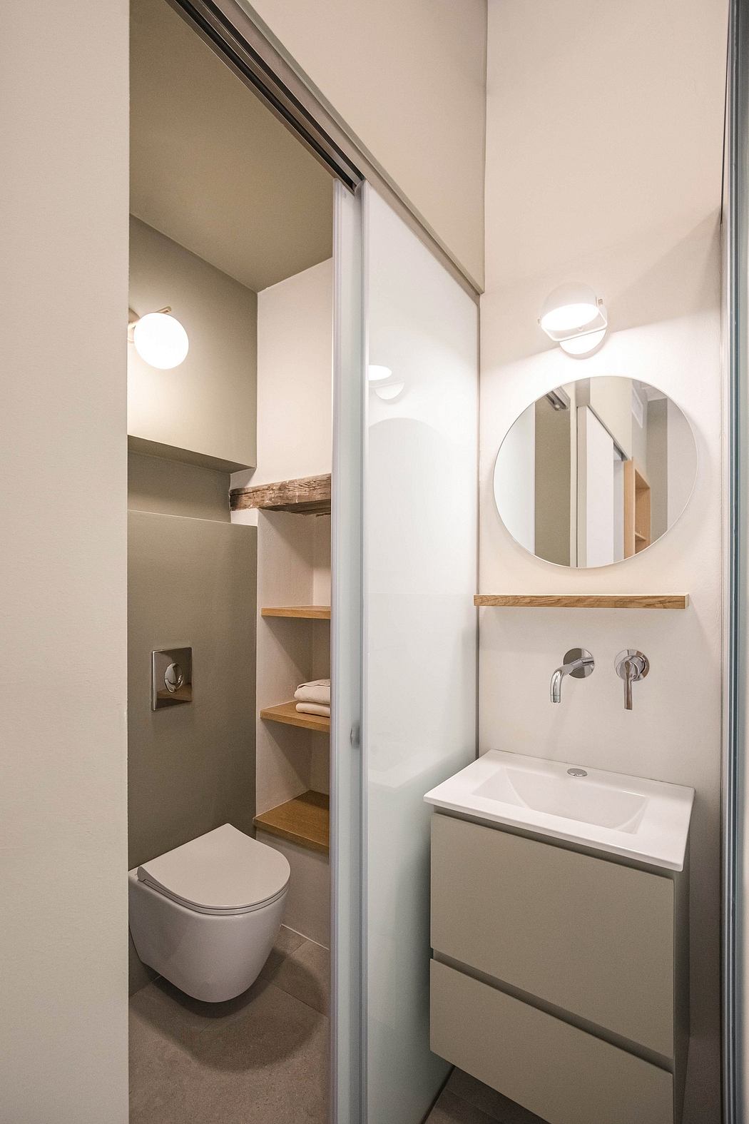 Modern bathroom with sliding glass doors, floating vanity, and round mirror.