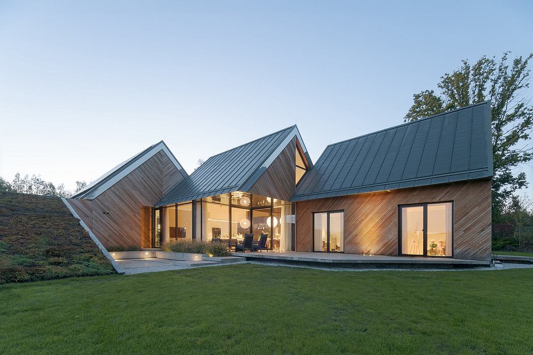 Modern angular architecture with dramatic sloping roofs and glass walls overlooking lush greenery.