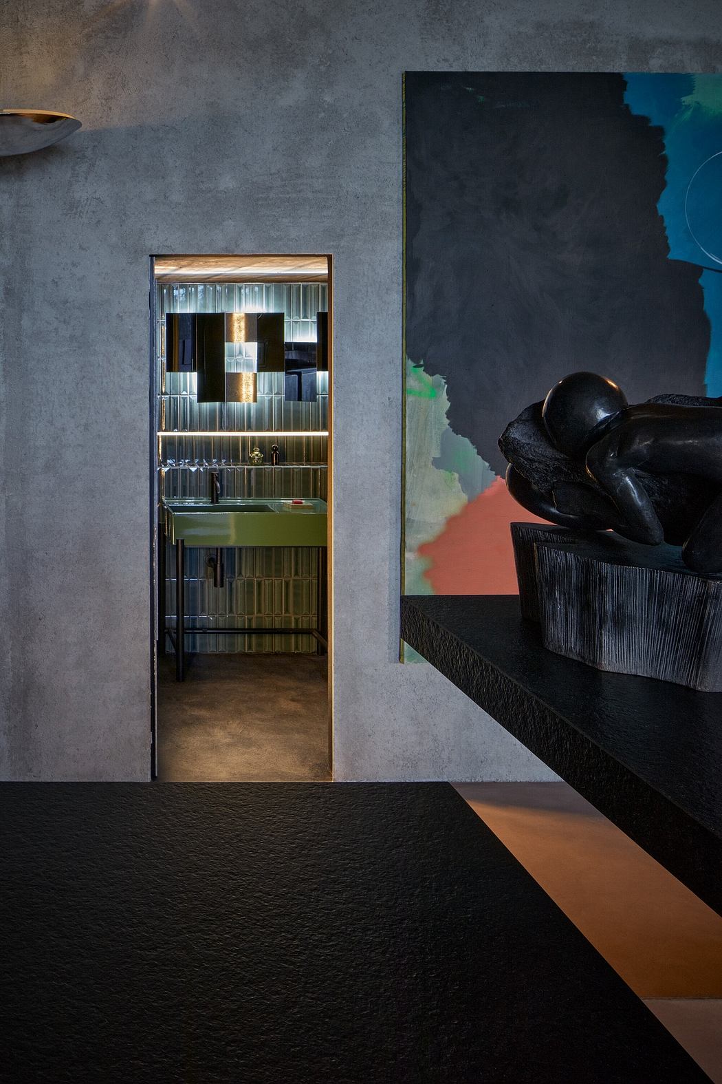 A modern, minimalist interior featuring a sleek black furniture piece, a textured wall, and an illuminated display cabinet.