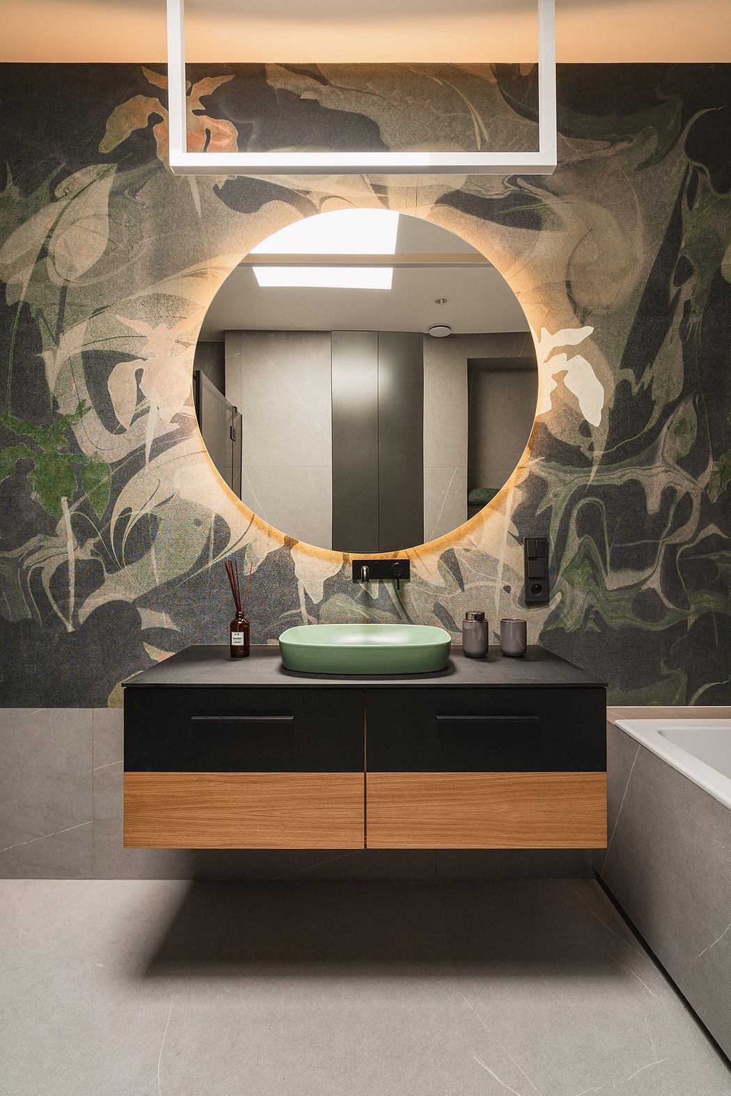A modern bathroom vanity with a round mirror and intricate wallpaper pattern.