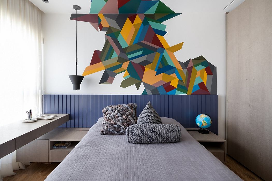 A vibrant geometric mural adorns the wall above a cozy, minimalist bedroom setup.