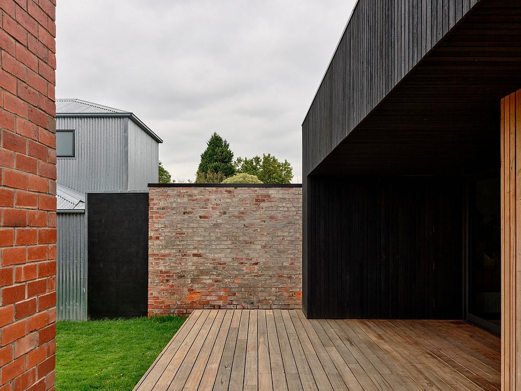 A modern, minimalist exterior with brick walls, wooden decking, and metal siding.