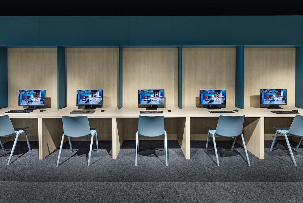 A modern computer room with sleek wooden desks, gray chairs, and multiple monitors.