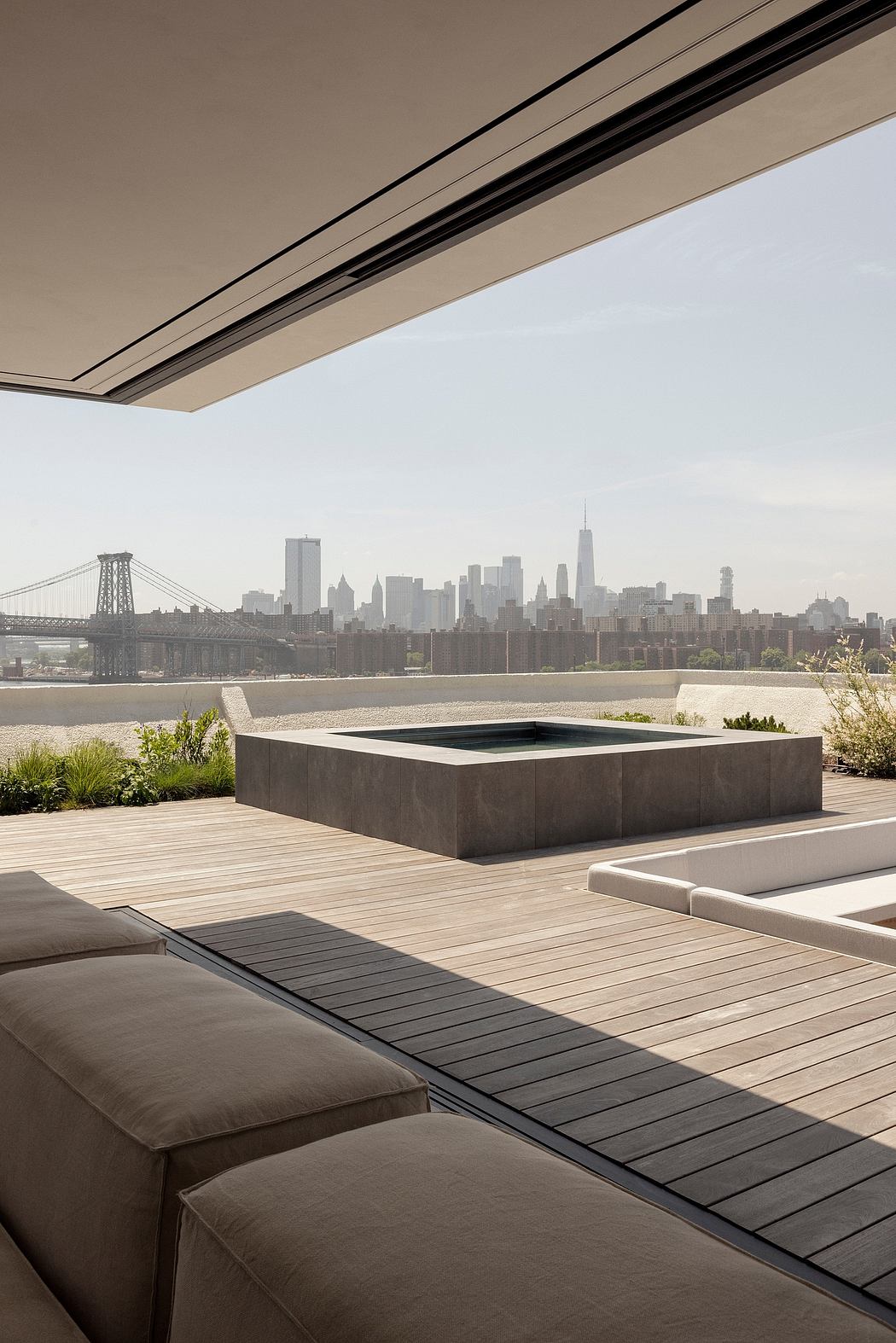 A modern deck overlooking a cityscape with a sleek water feature and minimalist furniture.