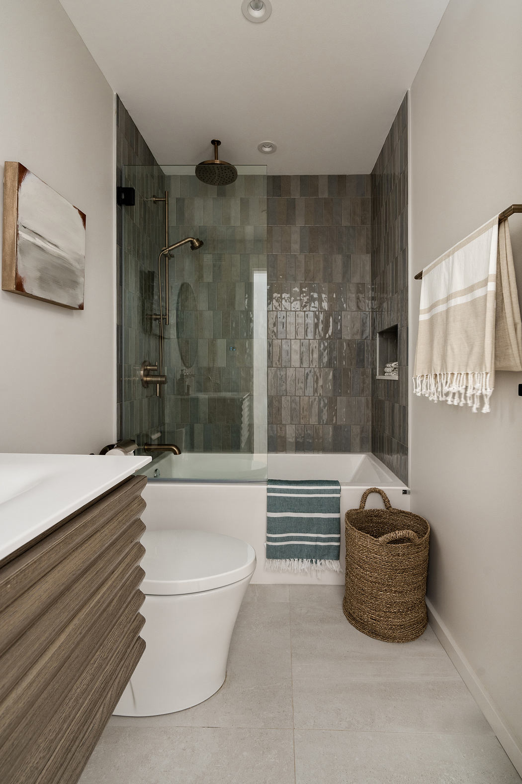 Sleek modern bathroom with gray tile walls, wooden vanity, and woven basket storage.