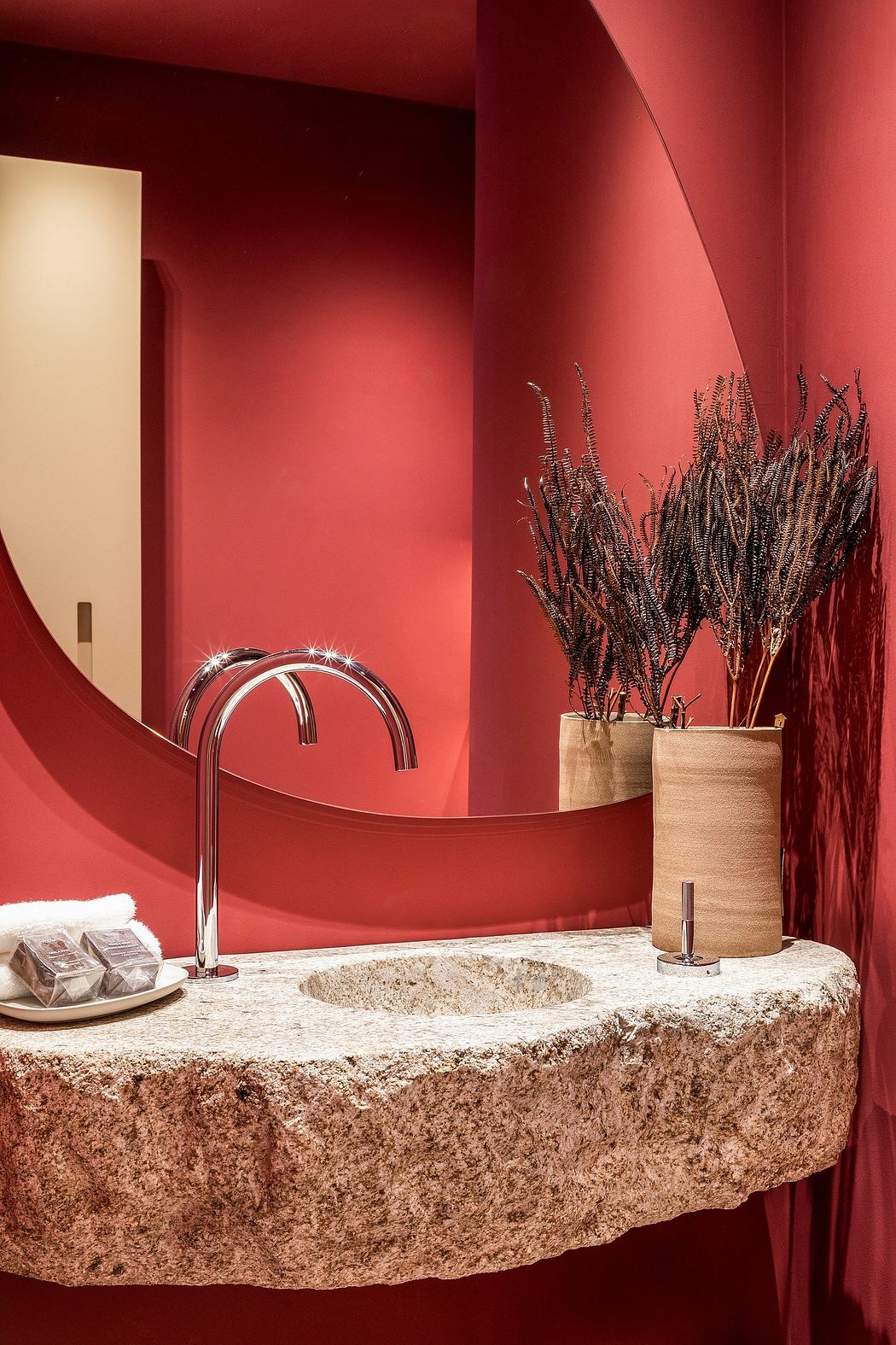 A modern, luxurious bathroom with chrome faucet, stone vanity, and ornamental branches.