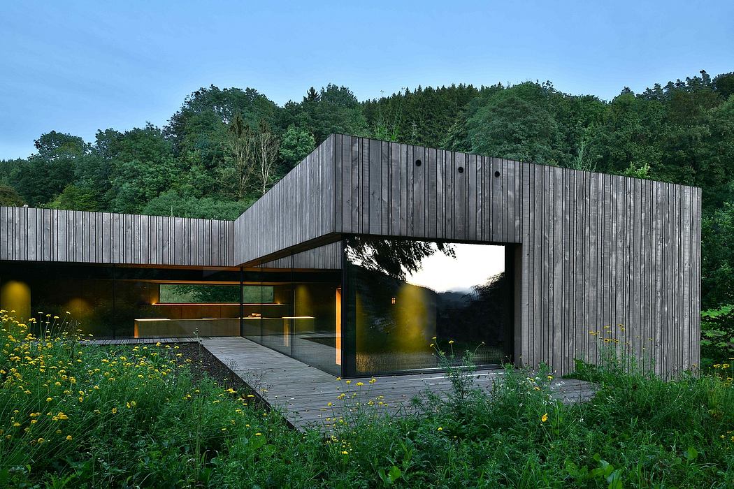 Striking modern structure with wooden facade and expansive glass windows overlooking greenery.