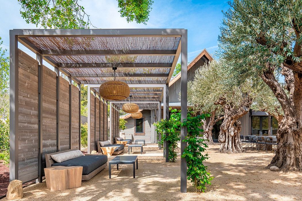 Rustic outdoor patio with wooden pergola, woven light fixtures, and lush greenery.