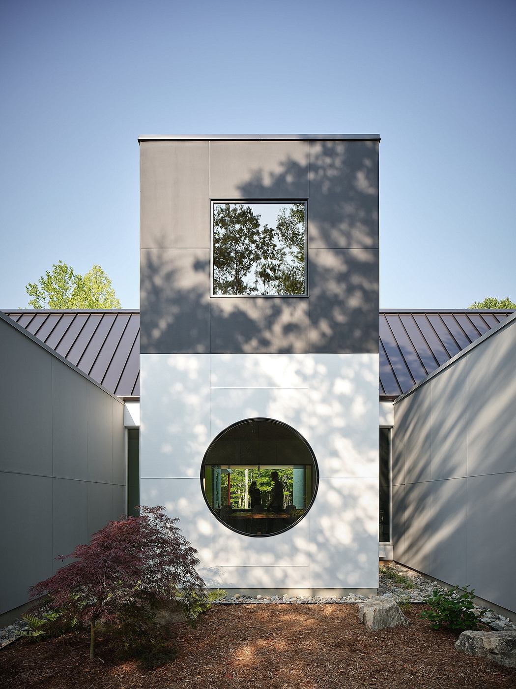 Sleek, modern architecture with large circular window framing lush greenery.