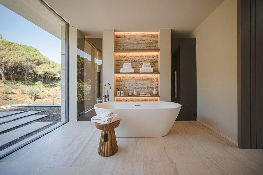 Spacious bathroom with modern freestanding tub, shelving, and view of natural scenery.