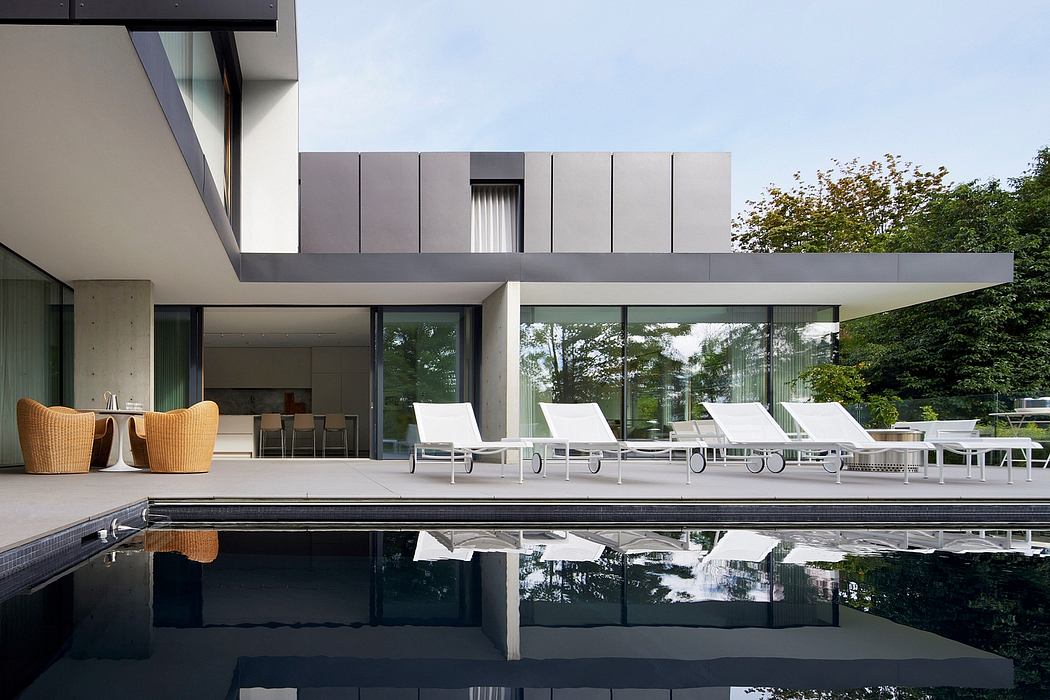 A modern architectural exterior with pool, lounge chairs, and surrounding foliage.