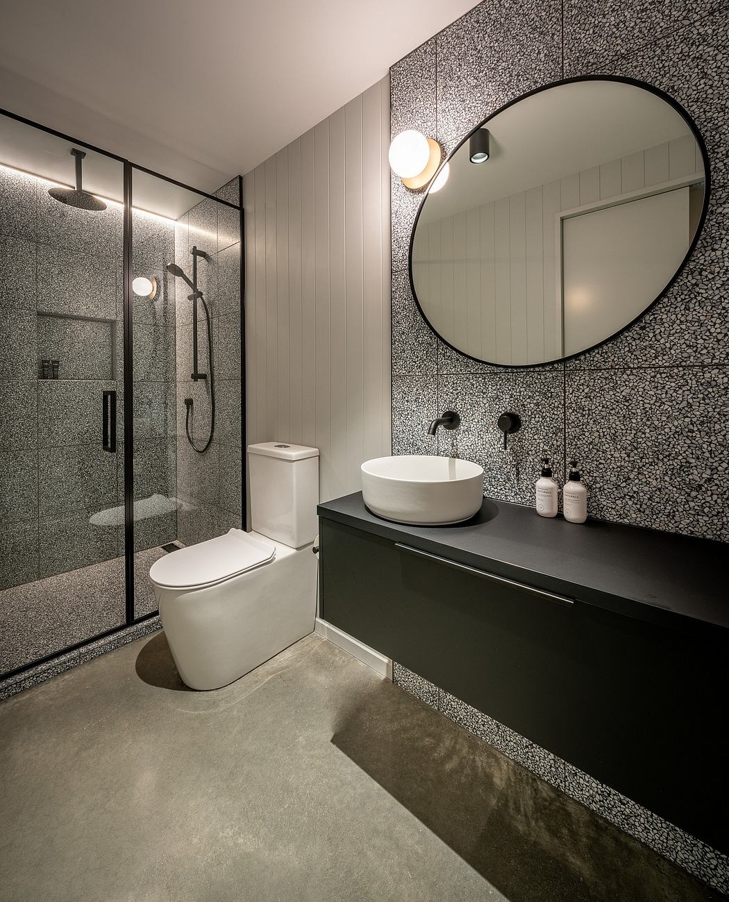 Sleek, modern bathroom design with a round mirror, vessel sink, and textured wall panels.