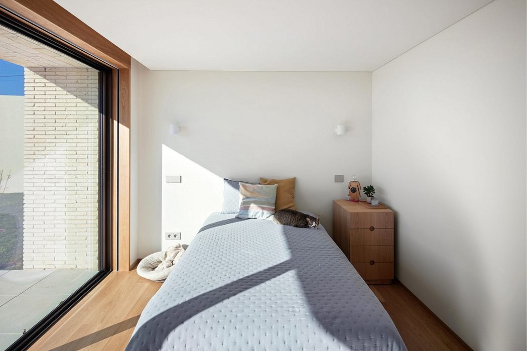 Minimalist bedroom with large window, wooden furniture, and cozy bedding.