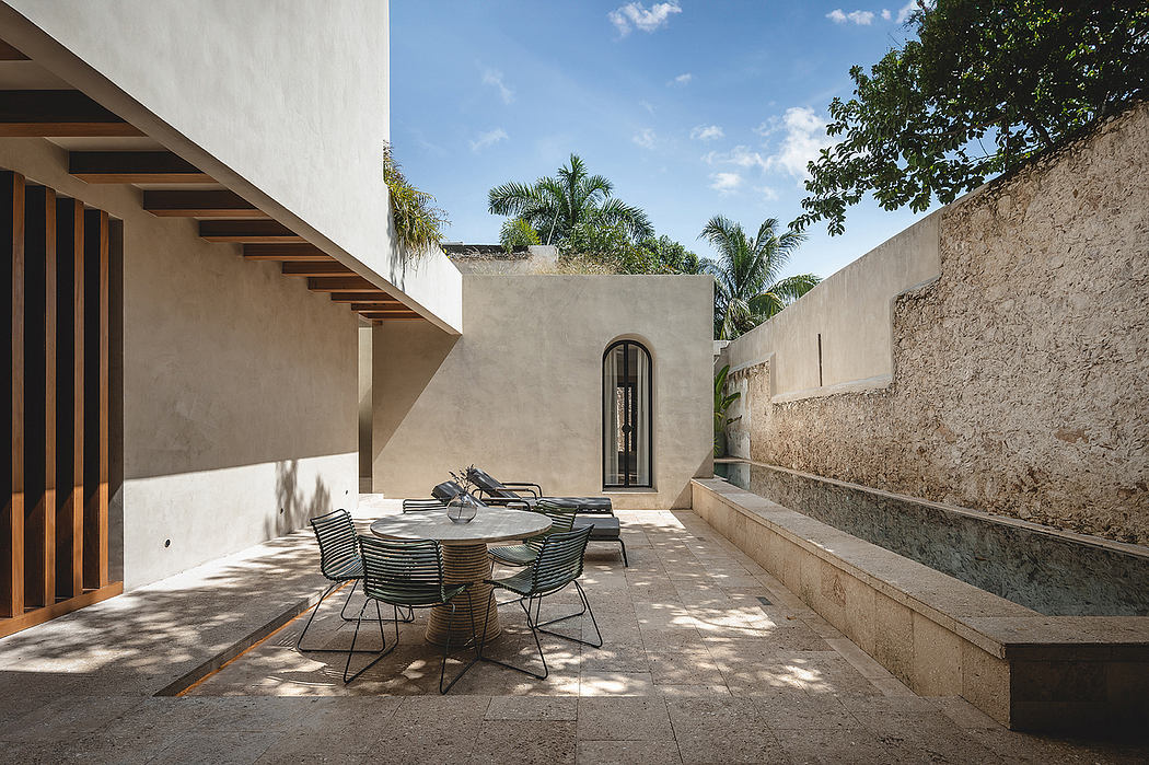 Minimalist outdoor patio with a round dining table, wicker chairs, and palm trees surrounding the space.
