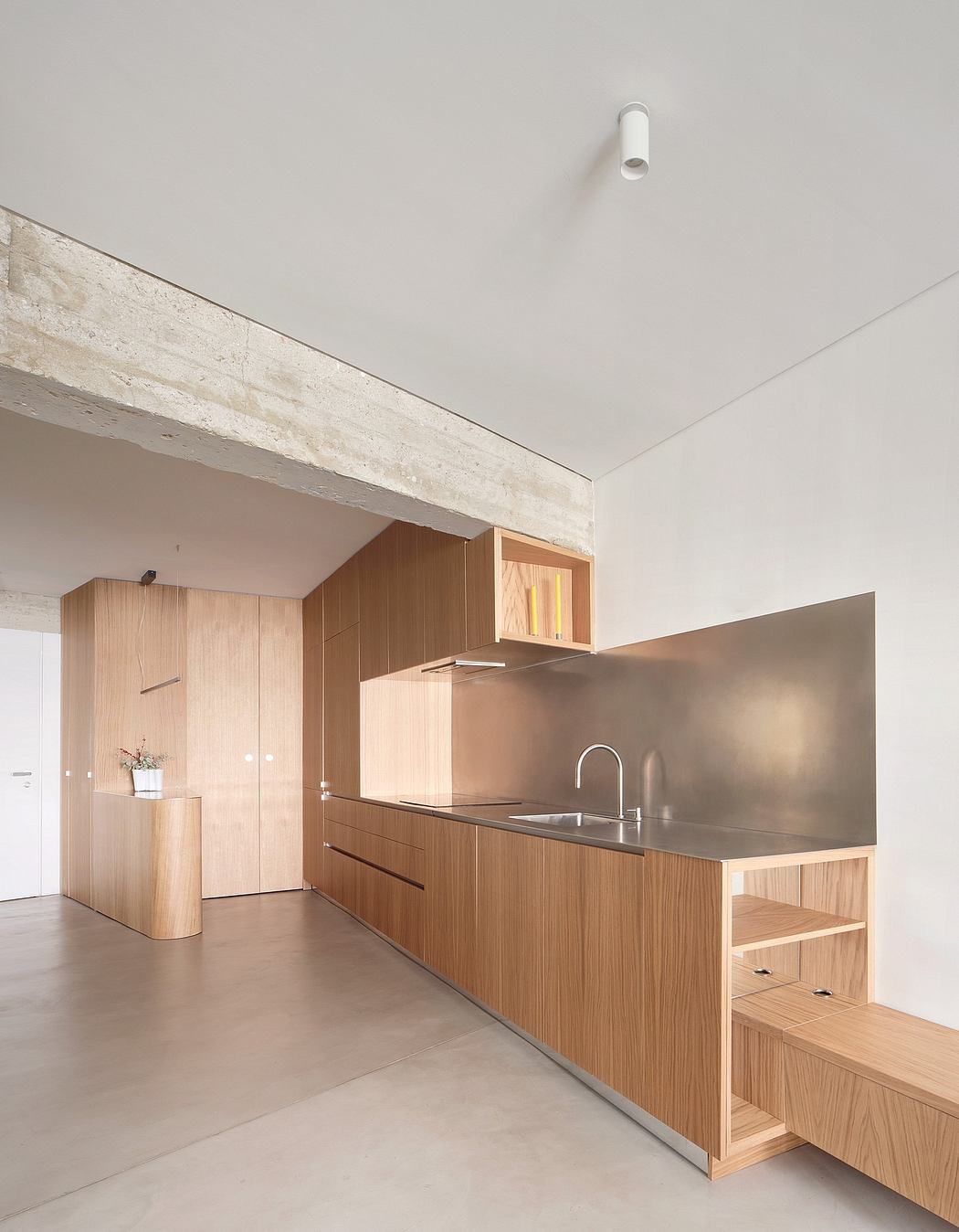 Minimalist kitchen design featuring wooden cabinetry, stainless steel appliances, and concrete flooring.