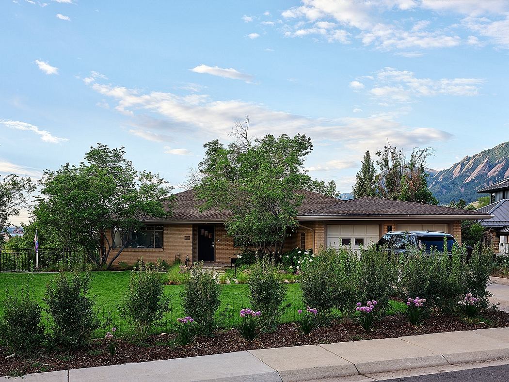 A ranch-style home with a well-manicured yard, featuring lush greenery and vibrant flowers.