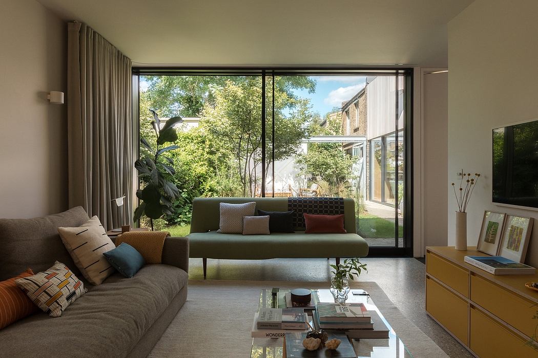 Spacious living room with large windows, modern furnishings, and lush greenery outside.