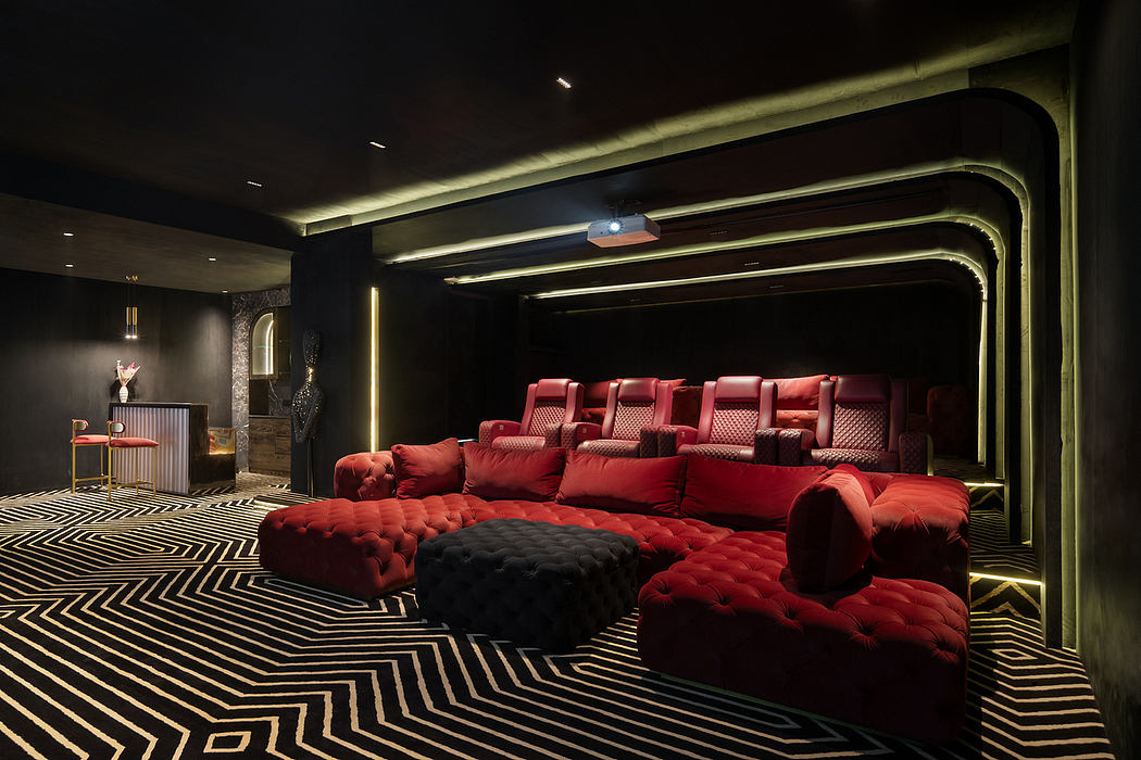 Luxurious home theater with plush red seating, sinuous architectural lighting, and geometric patterned floor.