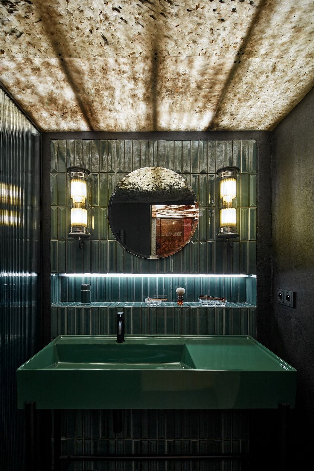 Dramatic bathroom with textured ceiling, green glass tile accents, and circular mirror.